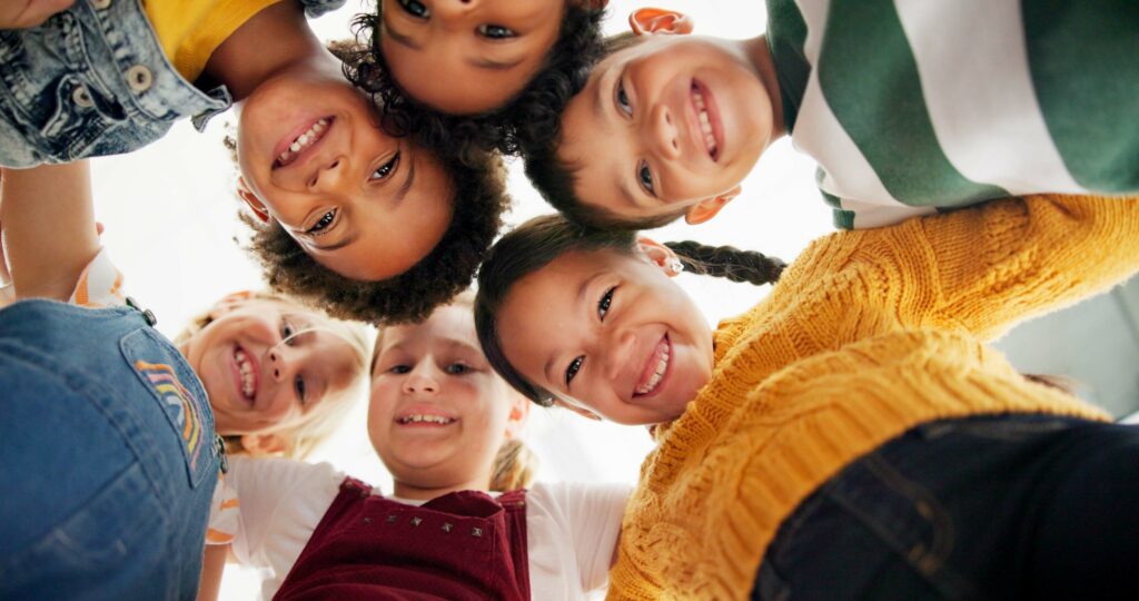 Children huddled together smiling while playing.