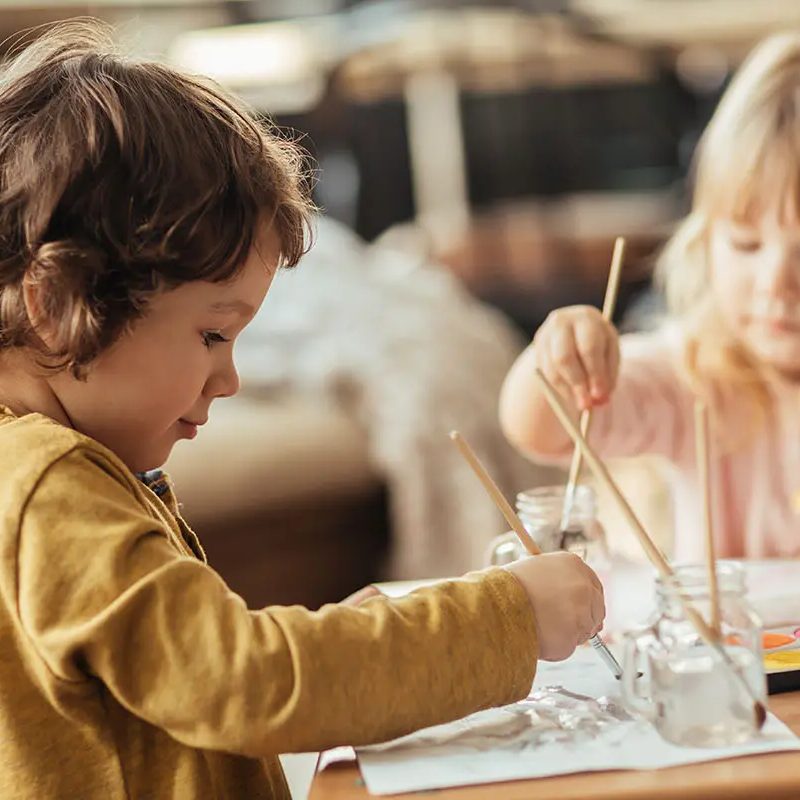 h-16 Two children painting at a table with water colors during art class at Building Brilliance Day Care Long Island City.